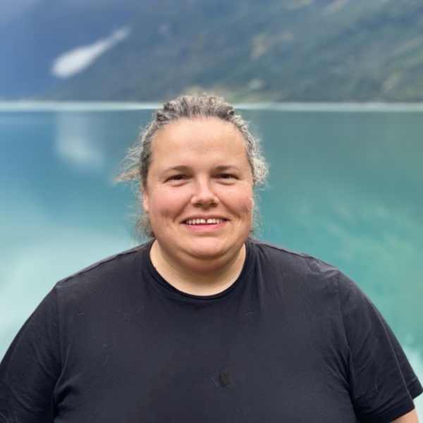 Dame med svart tskjorte og sjø i bakgrunnen